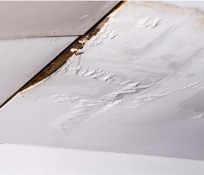 "a white ceiling showing signs of water damage from a leak "