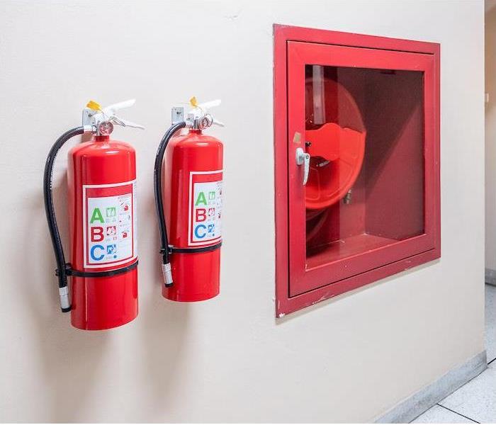 "two fire extinguisher hanging on a tan interior wall  